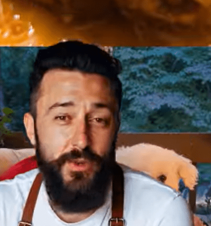 A bearded man cooking with an intense expression.