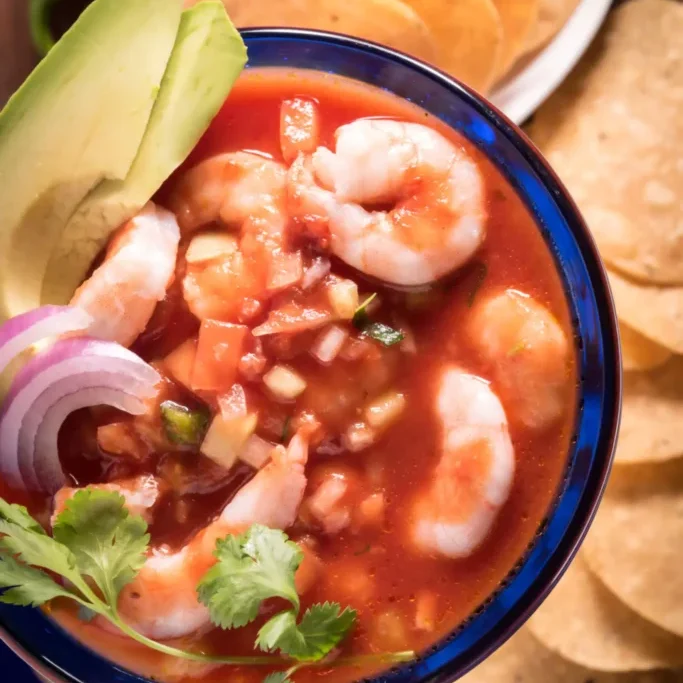 A bowl of shrimp ceviche garnished with avocado and cilantro.