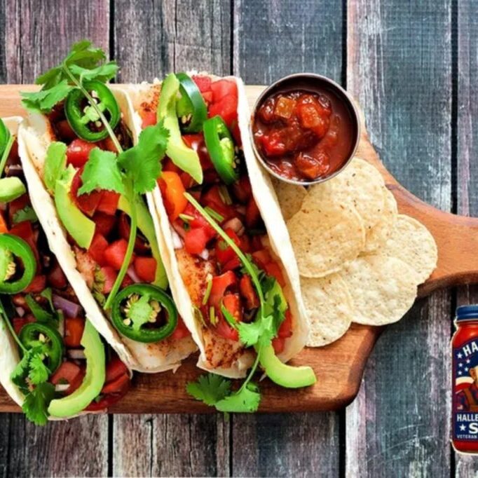 Three colorful tacos with fresh toppings on a wooden board.