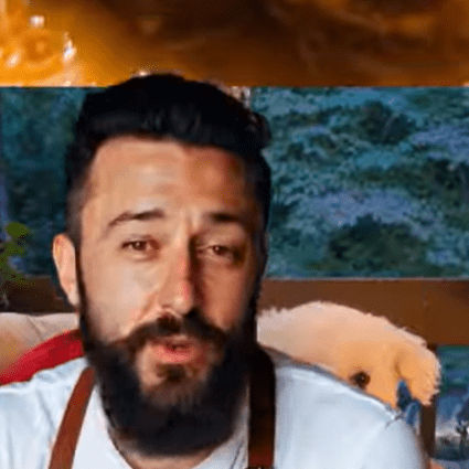 A bearded man cooking with an intense expression.